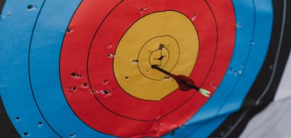 Close-up of a target in archery with a single arrow hitting the bullseye, showcasing precision and skill.
