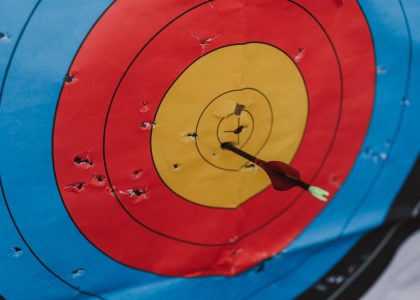 Close-up of a target in archery with a single arrow hitting the bullseye, showcasing precision and skill.